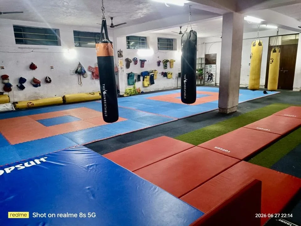 Hanging punching bags above colourful training mats at the academy