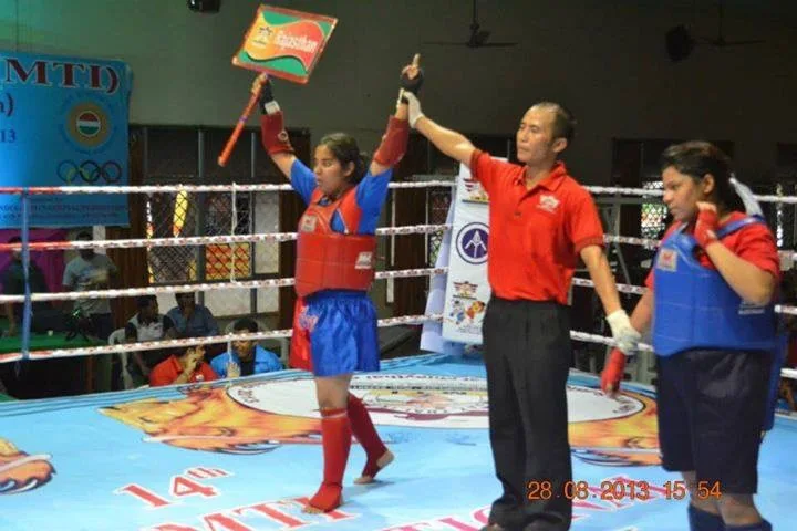 Richa Gaur with her arm raised by a referee in a competition ring